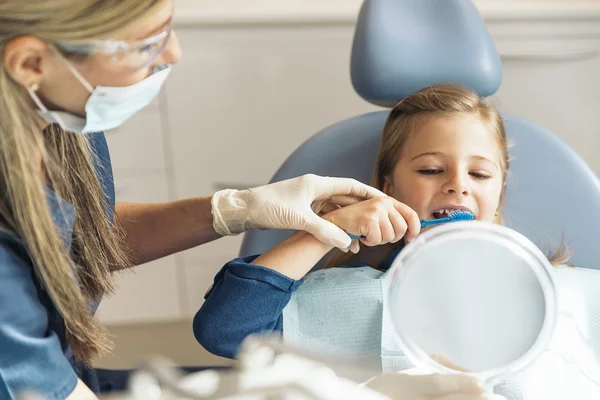 Médico dentista ensinando uma criança a escovar os dentes — Fotografia de Stock