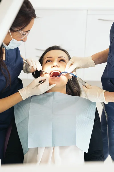 Dentistas con un paciente durante una intervención dental . — Foto de Stock