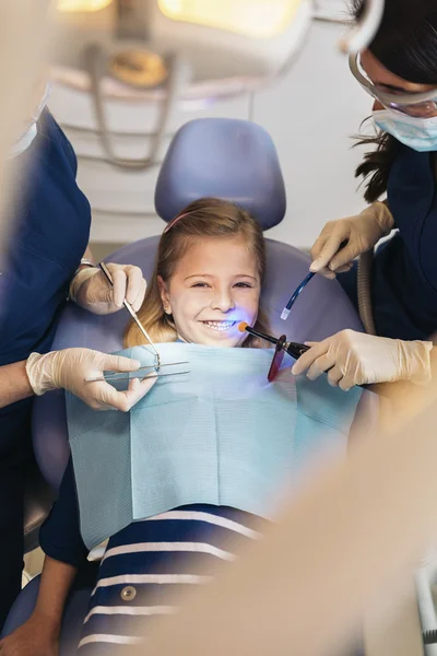 Dentists with a patient during a dental intervention to girl. — Stock Photo, Image