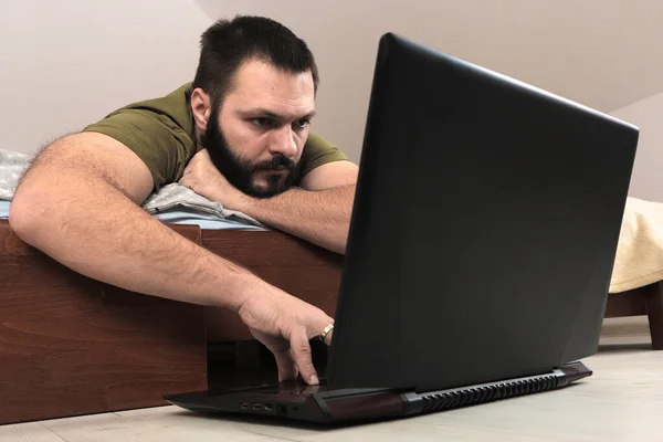 Молодой Человек Бородой Лежит Животе Кровати Использует Ноутбук Выборочный Фокус — стоковое фото