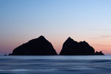 Güneş batarken Holywell körfezi, Cornwall, İngiltere, Carter Adaları 'nın üstünde.