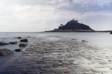 Cornwall İngiltere 'deki muhteşem St. Michaels binası. Marizion limanından bakan kayalardan oluşan bir ön planda.