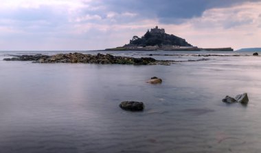 Cornwall İngiltere 'deki muhteşem St. Michaels binası. Marizion limanından bakan kayalardan oluşan bir ön planda.