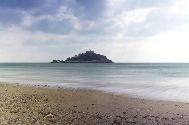 Cornwall İngiltere 'deki muhteşem St. Michaels binası. Marizion limanından bakan kayalardan oluşan bir ön planda.