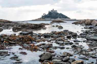 Cornwall İngiltere 'deki muhteşem St. Michaels binası. Marizion limanından bakan kayalardan oluşan bir ön planda.