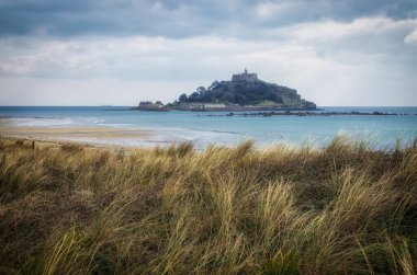 Cornwall İngiltere 'deki muhteşem St. Michaels binası. Marizion limanından bakan kayalardan oluşan bir ön planda.