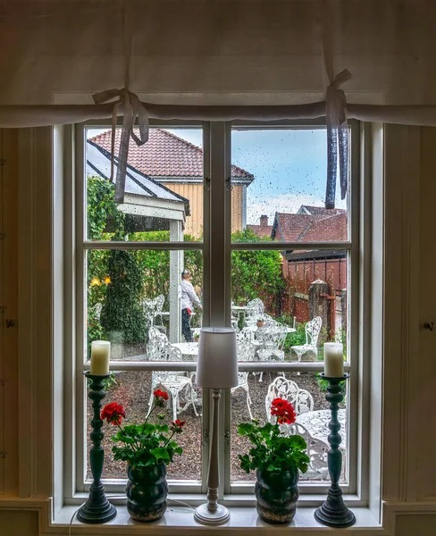 Vadstena, Sweden - May 23, 2021: Cosy decorated window with a view toward backyard during the rain falling