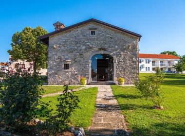 Lipica, Slovenya - 8 Ağustos 2025: Çimenli bir alanda kemerli girişi olan taş bina, açık gökyüzü.