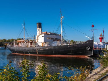 Stockholm, İsveç - 3 Ekim 2025: Açık mavi gökyüzünün altındaki bir limana demirlemiş tarihi buharlı gemi.