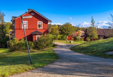Kırsal bir köy manzarası, kırmızı ahşap evler ve dolambaçlı bir yol..
