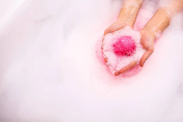 Bola de sal de banho se dissolve nas mãos. Bomba de banho colorida Fotos De Bancos De Imagens