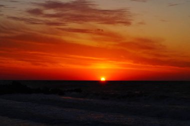 Sıcak bir yaz sabahında dalgalarla deniz kıyısında gün doğumu