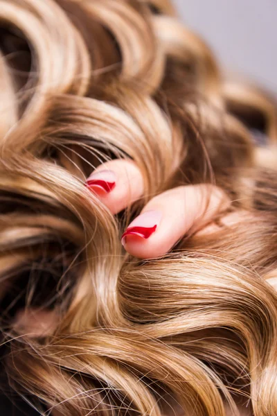 Corda de cabelo louro encaracolado em seu braço — Fotografia de Stock