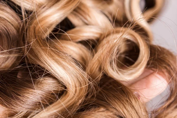 Corda de cabelo louro encaracolado em seu braço — Fotografia de Stock