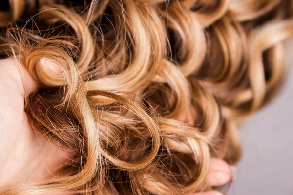 Corda de cabelo louro encaracolado em seu braço — Fotografia de Stock