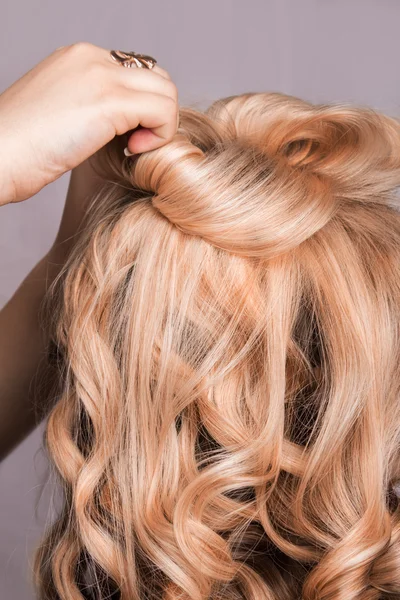 Corda de cabelo louro encaracolado em seu braço — Fotografia de Stock