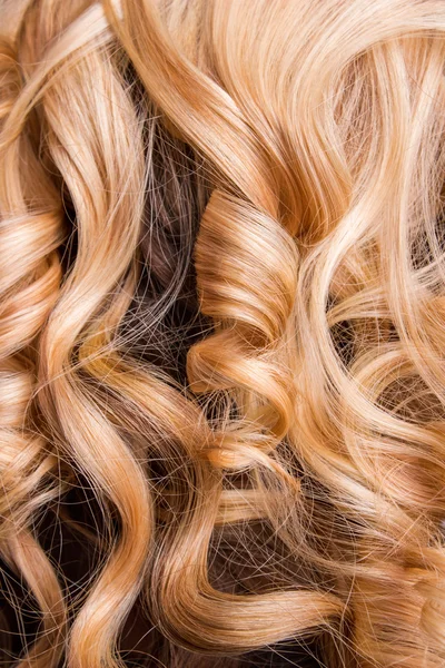 Strand kudrnaté blond vlasy na ruce — Stock fotografie