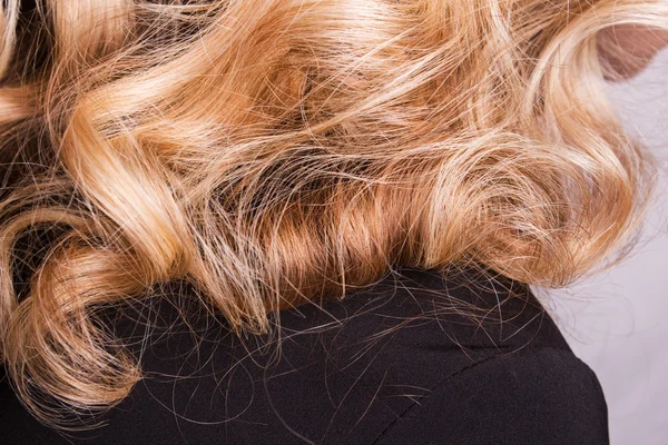 Strand van krulhaar blond op zijn arm — Stockfoto