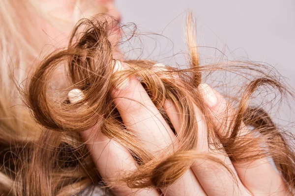 Corda de cabelo louro encaracolado em seu braço — Fotografia de Stock