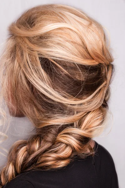Strand kudrnaté blond vlasy na ruce — Stock fotografie