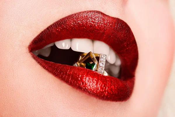 Close-up van mooie vrouw lippen met heldere mode donker rode glanzende make-up. Macro lipgloss cherry make-up. Mond met bruiloft gold diamond ring — Stockfoto