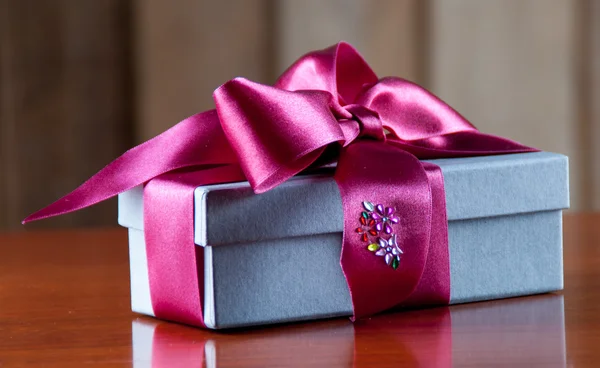 Holiday Gift Packed into Grey Box with Purple Ribbon on Glossy W — Stock Photo, Image