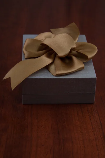 Holiday Gift Packed into Grey Box with Ribbon on Glossy Wooden T — Stock Photo, Image