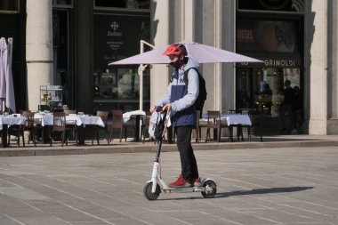 Milano sokaklarında mobiletli insanlar. Tecritten sonra şehir hareket kabiliyeti değişiyor. Şehirdeki insanlar yeni ulaşım araçlarıyla seyahat ediyorlar..
