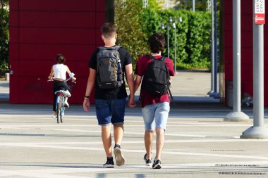 Piazza Gino Valle (Gino Valle Meydanı) 'nda yürüyen erkek çift 