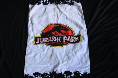 Bir parça kumaşın üzerinde dramatik bir Jurassic Park ekran baskısı olan tatil hatıraları.