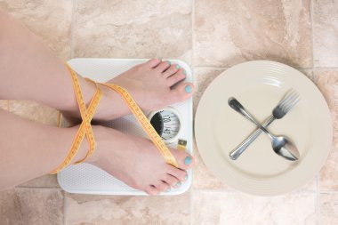 Woman standing on a weight scale clipart