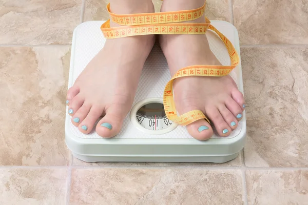 Kobieta stojąc w skali wagi — Zdjęcie stockowe