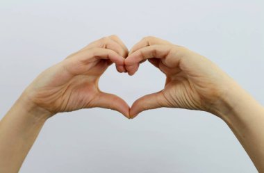 Yakın plan, kadının elleri kalp sembolü oluşturuyor.