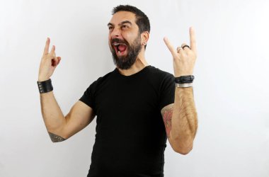 Sakallı, siyah tişörtlü ve beyaz izole edilmiş arka planda dövmeleri olan genç bir adam elleri havada kayanın suyunu çıkarırken çılgınca bir ifadeyle bağırıyor. Heavy metal konsepti