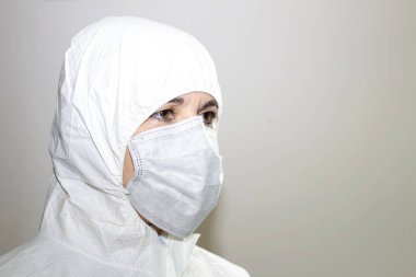 Yakın plan, Coronavirus 'la savaşmak için önlüklü ve koruyucu maskeli bir kadın sağlık görevlisi.