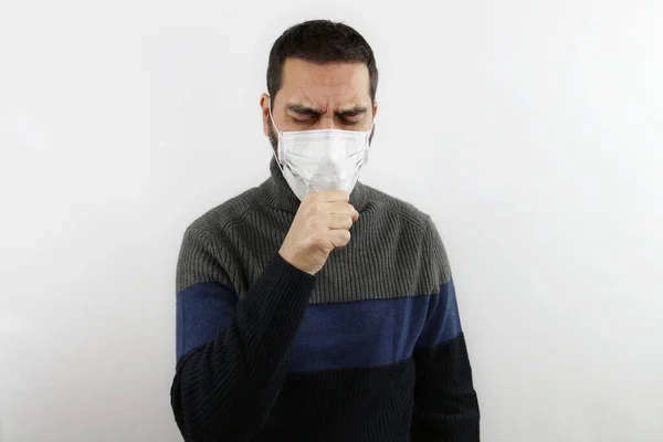 İzole edilmiş beyaz arka planda koruyucu bir tıbbi maske takmış eli ağzının önünde kapalı bir adam. Covid19 virüs konsepti