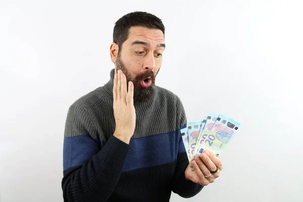 İzole edilmiş beyaz arka plandaki sakallı adam elinde 20 euro tutuyor ve yüzüyle hayret verici bir ifade sergiliyor. Kazanan konsept