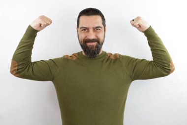 Sıradan kıyafetler giyen sakallı adam gururla gülümseyen kol kaslarını gösteriyor. fitness konsepti.