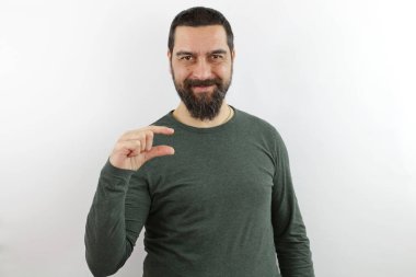 Sıradan kıyafetler giyen sakallı adam gülümseyen ve kendine güvenen el hareketleriyle parmaklarıyla küçük boy işareti yapan. ölçüm kavramı.