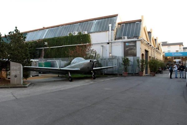 Pontedera, Pisa, İtalya - 26 Ekim 2019: P 148 Piaggio eğitim uçağıyla Piaggio Müzesi 'nin girişi ve arka planda Piaggio Lokomotif Motrice MC2 DE 54 