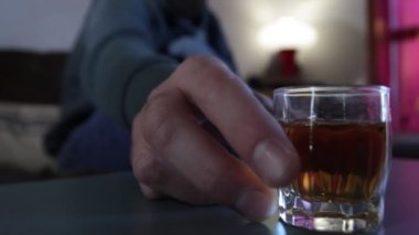 Bir erkeğin yudumlamak için içtiği bir bardak viskiyi yakından çek.