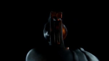 Siyah arka planda ateş eden adamın eli. Silahlı ve deri eldivenli bir suçlu..