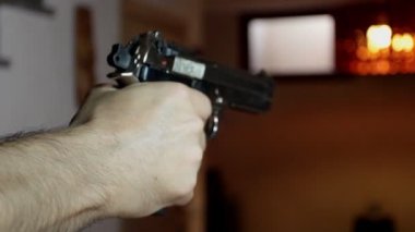 Bir katilin tuttuğu bir silaha yaklaşır, nişan alır ve ateş eder.