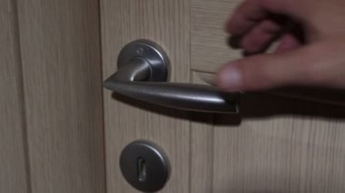 Bir adam kapıyı açarken elini kapı koluna koyar.