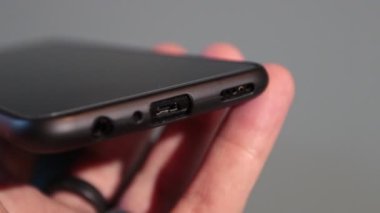 Yaklaş, adamın elleri akıllı telefonun şarj aletini yerleştiriyor.