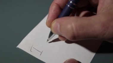 Yakın plan, bir adamın eli kağıda aşk mesajı yazıyor.