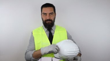 Sert şapka takan çekici mühendis kollarını kavuşturup kameraya bakıyor. Yavaş çekim.