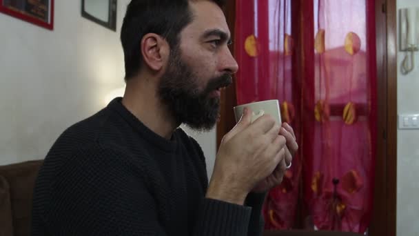 Przystojny Brodaty Mężczyzna Pije Filiżankę Gorącej Herbaty Kanapie Popołudniowa Przerwa — Wideo stockowe