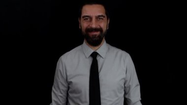 İzole edilmiş siyah arka planda gülümseyen sakallı iş adamı kolunu kaldırıyor ve eliyle 