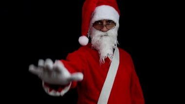 Siyah arka planda Noel Baba ciddi bir yüzle kolunu kaldırıyor ve dur işaretini eliyle yapıyor. Noel konsepti